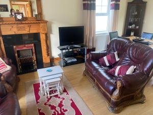 a living room with a leather couch and a table at Glenrandel Valley in Claudy
