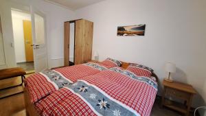 a bedroom with a bed with a red and white blanket at Appartement de vacances Les Jardins in Saint-Imier