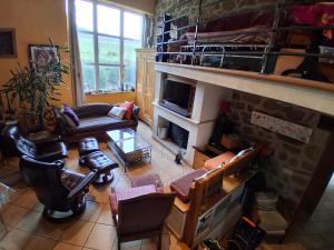 Una sala de estar con chimenea de piedra y sillones de cuero en Gîte Le Duzon, en Plats