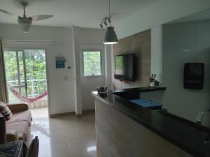 sala de estar con cocina con barra y TV en Apartamento Veleiros da Ilha - Praia do Tombo, en Guarujá