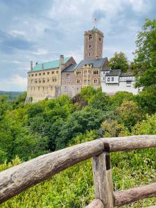 un castello in cima a una collina con una recinzione di legno di Schöne ruhige Ferienwohnung - in Eisenach mit Kamin - Nahe Karolinentalbrücke - Hund ja a Eisenach