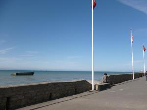 una persona seduta su un muro vicino all'oceano di Studio De La Mer ad Arromanches-les-Bains