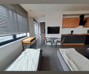 a room with two beds and a table and a kitchen at Apartament studio PIANO in Płock