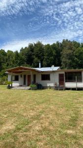 een wit huis met een grasveld voor bij Parcela Patty in Pucura