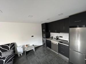 a kitchen with black cabinets and a stainless steel refrigerator at Apartamento leyda in Fuente el Saz