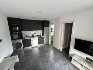 a kitchen with black cabinets and a sink and a dishwasher at Apartamento leyda in Fuente el Saz