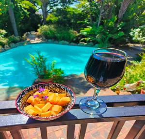 a glass of wine sitting next to a bowl of cheese at Hidden Gem Self-catering RUWARI BRACKENFELL CAPE TOWN in Cape Town