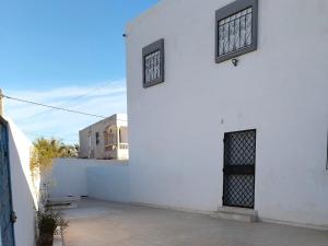 a white building with two windows on the side at appartement à louer Djerba in Al Maqārisah