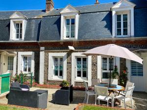 a table with an umbrella in front of a house at Etretat Maison Meublé 3 étoiles in Étretat