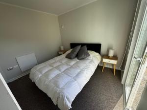 Un dormitorio con una cama blanca con dos almohadas encima. en Acogedora Casa Nueva, en Puerto Montt