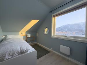 a bedroom with a bed and a large window at Cozy and Central Loft in Tromsø in Tromsø