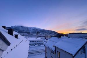 a city covered in snow with a mountain in the background at Cozy and Central Loft in Tromsø in Tromsø