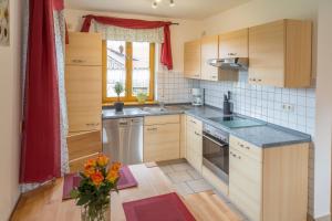 a kitchen with wooden cabinets and a vase of flowers at Ferienwohnung Rosalie in Westerndorf