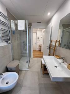 a bathroom with two sinks and a shower and a toilet at LikeHome PortaReno Monolocale Exclusive - 4 pxs in Ferrara