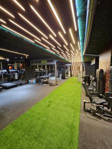 ein Fitnessstudio mit grünem Teppichboden und Beleuchtung in der Unterkunft Matar Residence Hotel Suites in Al Bawsharīyah