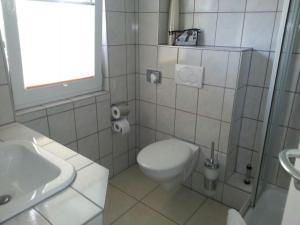 a white bathroom with a toilet and a sink at Residenz Seestern in Warnemünde