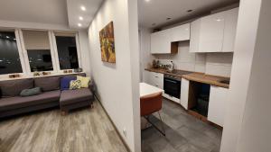 a kitchen and living room with white cabinets and a couch at Keep calm and relax in Gołdap