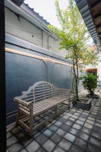 レギャンにあるKuta Beach Houseの木の隣のパティオに置かれた木製のベンチ