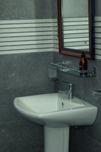 Un lavabo blanco en un baño con espejo. en Villa Sansun - Riverside Escape, en Weligama