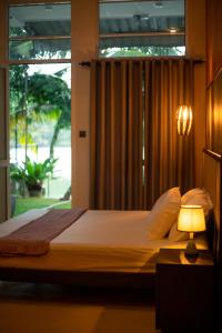 Un dormitorio con una cama con una lámpara y una ventana. en Villa Sansun - Riverside Escape, en Weligama 29 fotos más