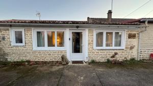 a brick house with a white door and windows at Meublé Chic AJACQUEE in Celles-sur-Belle