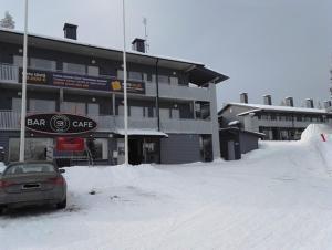 un aparcamiento cubierto de nieve frente a un edificio en Vuosselin Helmi Apartments, en Ruka