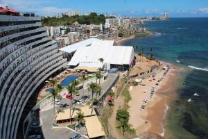 a view of a beach with a building and the ocean at Ondina Apart Hotel Cobetura in Salvador