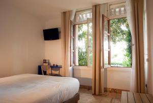 ein Schlafzimmer mit einem Bett und einem großen Fenster in der Unterkunft Hôtel Le Dauphin in Arcachon