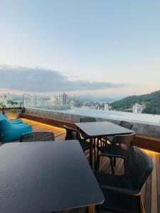 a balcony with tables and chairs on a roof at LOFT UP 506 | Mobiliado | WIFI | Piscina | Vaga in Blumenau