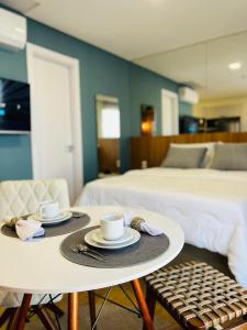 a room with two beds and a table with cups and plates at LOFT UP 506 | Mobiliado | WIFI | Piscina | Vaga in Blumenau