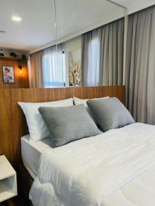 a bedroom with a white bed with two pillows at LOFT UP 506 | Mobiliado | WIFI | Piscina | Vaga in Blumenau