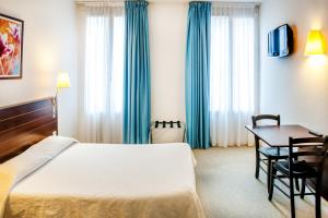 pokój hotelowy z łóżkiem i stołem w obiekcie Appart'hôtel Saint Jean w Lourdes