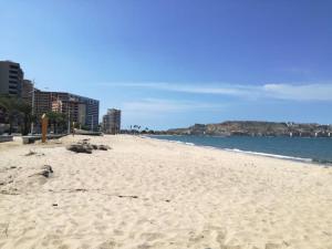 a sandy beach with buildings and the ocean at Comfortable and perfect location in Lechería in El Morto de Barcelona