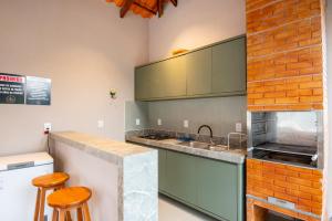 a kitchen with green cabinets and a counter with stools at Bangalôs da chapad in Vale do Capao