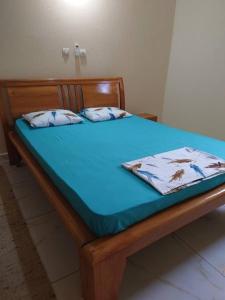 ein Holzbett mit einem blauen Laken und Kissen darauf in der Unterkunft Red Villa on Lionsrest 