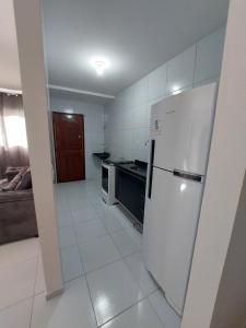 a white kitchen with a refrigerator and a couch at Nosso lar in Campina Grande