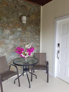 un tavolo con un vaso di fiori e due sedie di Serenity at Buccoo, Ensuite Room a Buccoo
