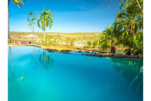 a large pool of blue water with palm trees at El Questro - The Homestead in Kununurra