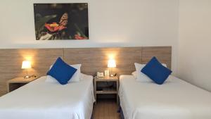 two beds in a room with two blue pillows at Hotel Los Viñedos in Lemos