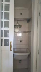a white bathroom with a sink and a toilet at Apartamento Temporada Guarujá Four Seasons in Guarujá