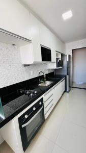 a kitchen with white cabinets and a sink and a refrigerator at Lindo Apartamento na Praia de Itapuã - Vila Velha -com ar condicionado na 2 quadra do mar ES in Vila Velha