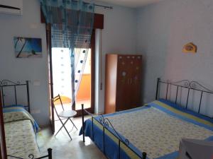 a bedroom with two beds and a window and a chair at B&B Figli Dei Fiori in Realmonte