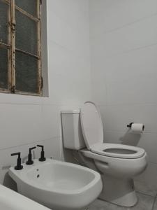 een witte badkamer met een toilet en een wastafel bij Casita Verde in Rosario