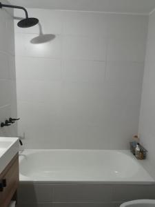 een witte badkamer met een bad en een wastafel bij Casita Verde in Rosario +2 foto's