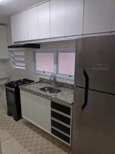 eine Küche mit Kühlschrank und Spüle in der Unterkunft Apto completo com varanda gourmet a 50 mt da praia in Bertioga