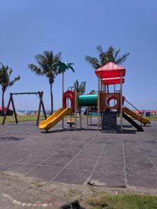 einen Park mit einem Spielplatz mit Rutschen und Palmen in der Unterkunft Apto completo com varanda gourmet a 50 mt da praia in Bertioga + 39 Fotos