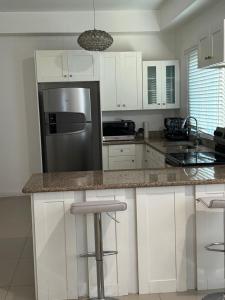 a kitchen with white cabinets and a stainless steel refrigerator at Harloes Suites - Kingston - Free Parking and Pool in Kingston