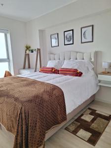 a bedroom with a large white bed with red pillows at Depa de estreno y garaje gratuito in Lima