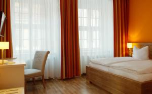 a bedroom with a bed and a chair and windows at Hotel Am Obermarkt in Freiberg +46 photos