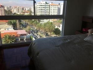 a bedroom with a bed and a large window at Pórtico tower in Cochabamba